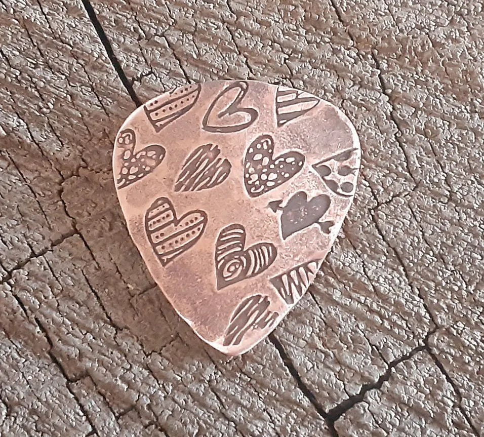 Copper guitar pick with hearts and hammered patterning