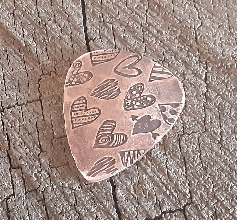 Copper guitar pick with hearts and hammered patterning