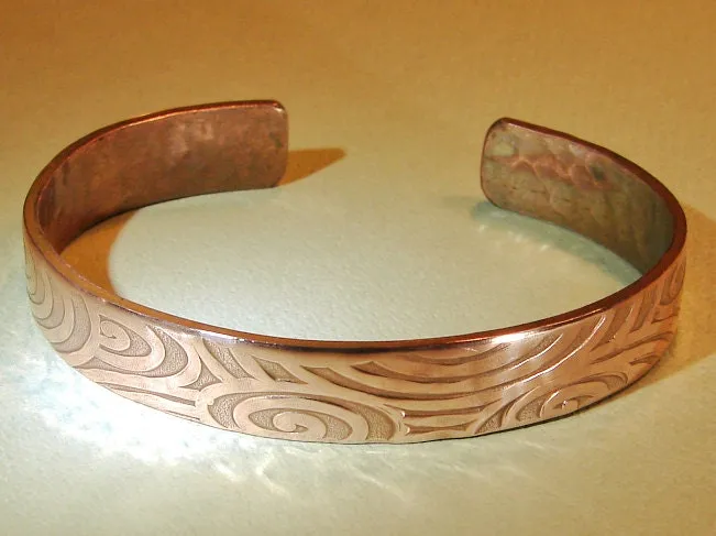 Swirling design on a cuff bracelet in heavy copper