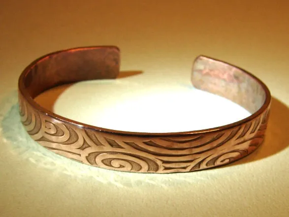 Swirling design on a cuff bracelet in heavy copper
